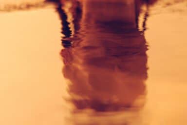 A face reflected in water, appearing distorted, symbolizing the impact of narcissistic personality disorder.